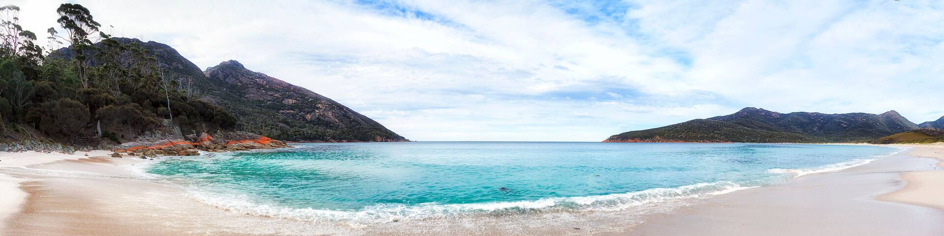 Panorama of white sands and pristine waters on Wineglass bay beach of Tasmanian Freycinet peninsula and remote national park.