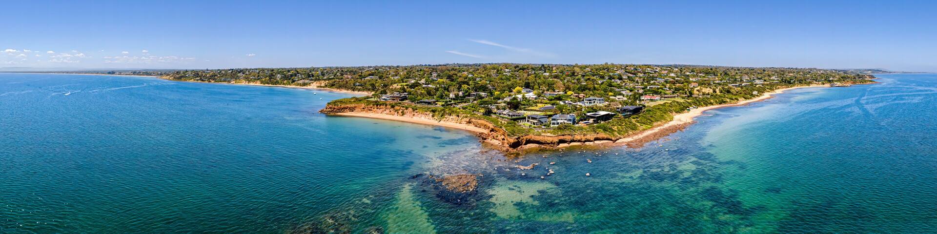 Aerial shot of Daveys Bay Pelican Point, Mount Eliza coastal seascape with turquoise sea and clear blue sky aerial panoramic