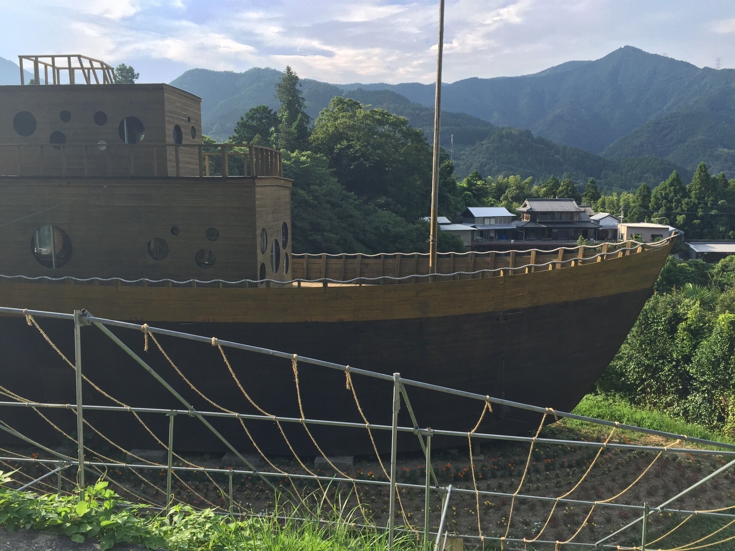 A large shipwreck in a forested area with mountains in the background.