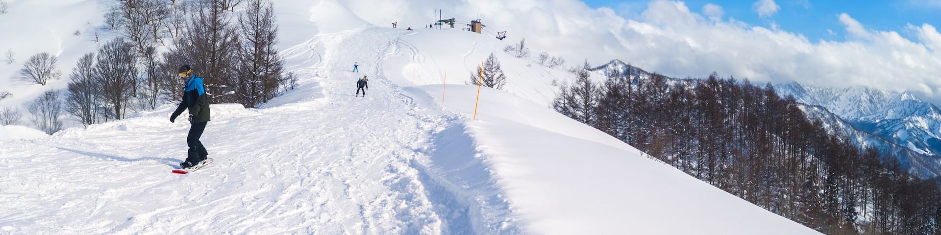 Panoramic view of the ski resort top showing the contrast between a tracked slope and fresh powder snow (Maiko, Minamiuonuma, Niigata, Japan)