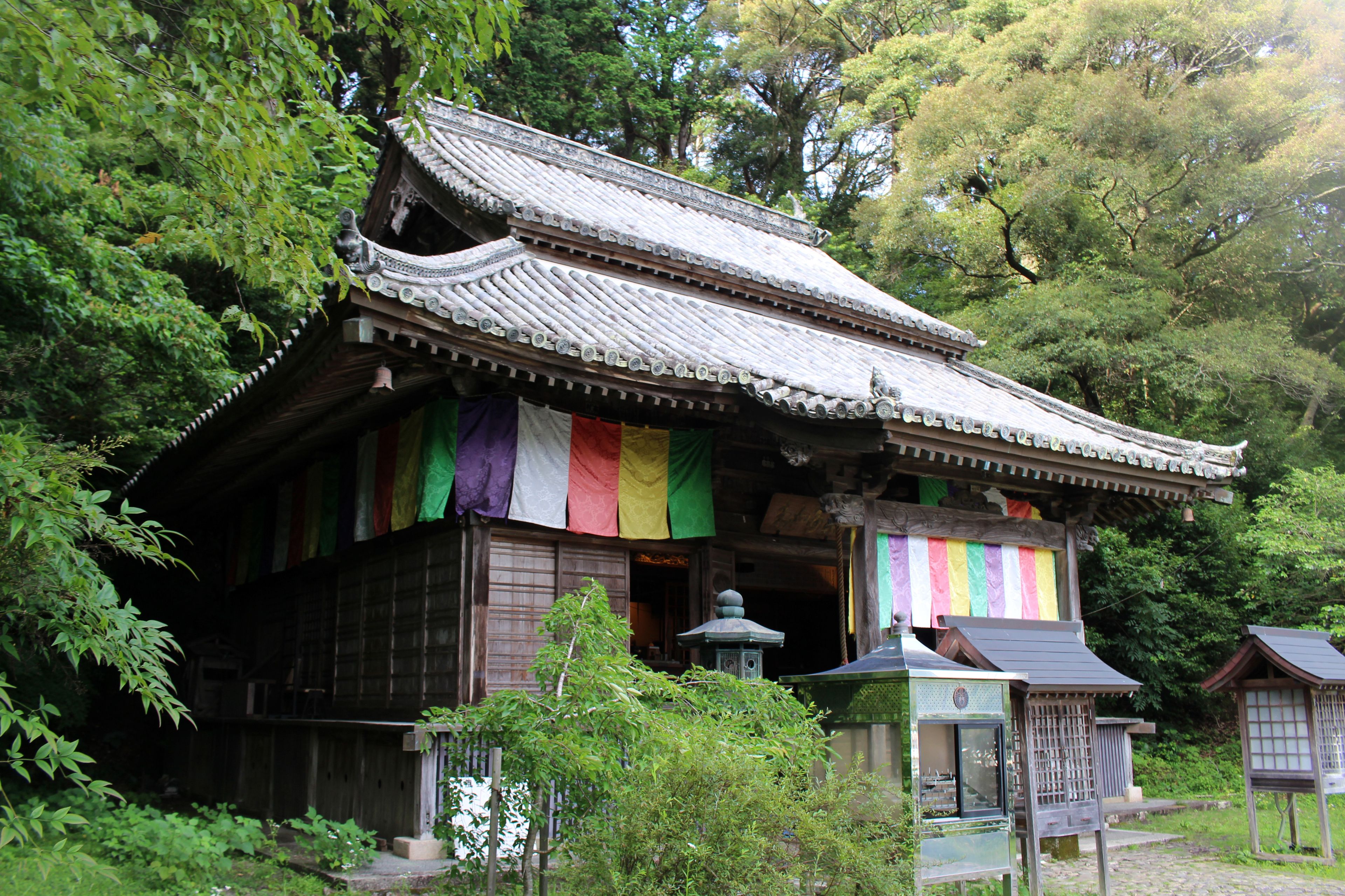 A traditional Japanese building with a tiled roof and colorful flags.