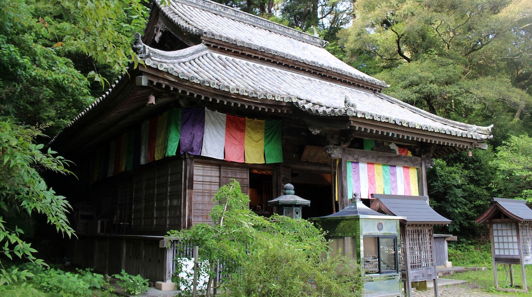 A traditional Japanese building with a tiled roof and colorful flags.