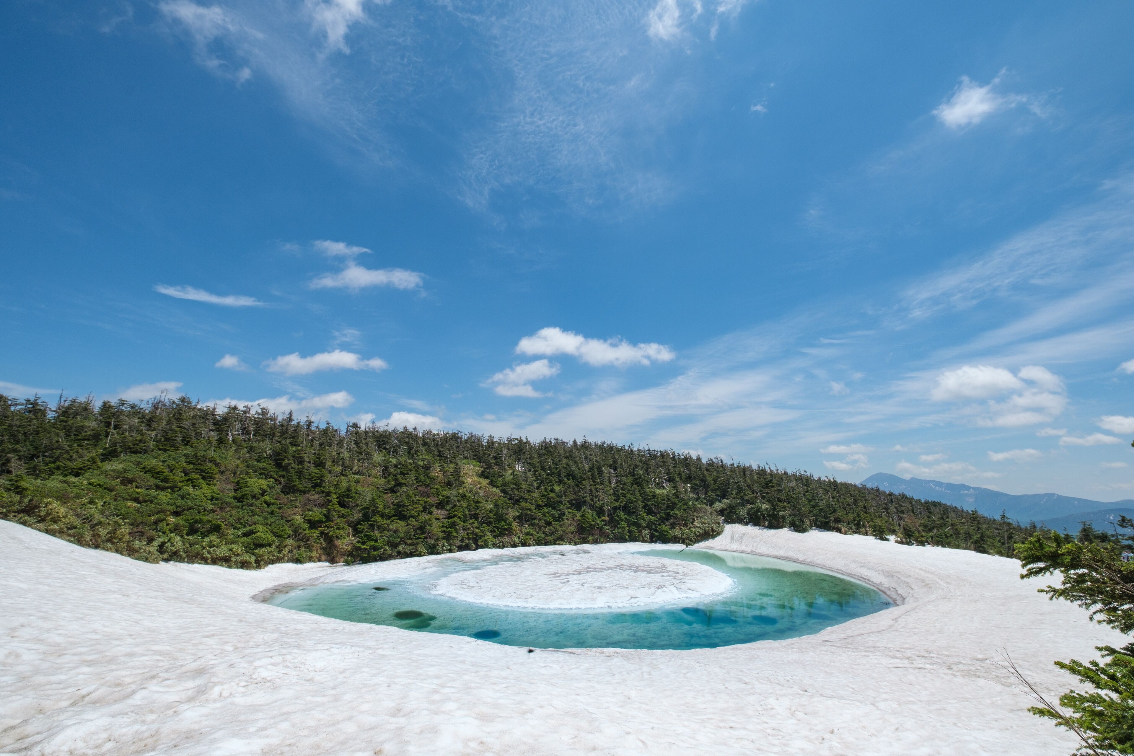 Un lago glaciar rodeado de nieve y bosque.
