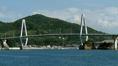 A bridge over water with a green hill in the background.