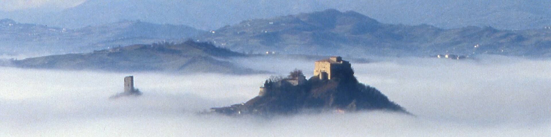 A castle on a hill surrounded by fog.