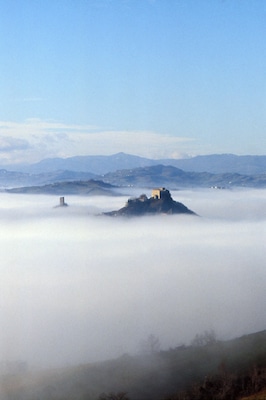 A castle on a hill surrounded by fog.