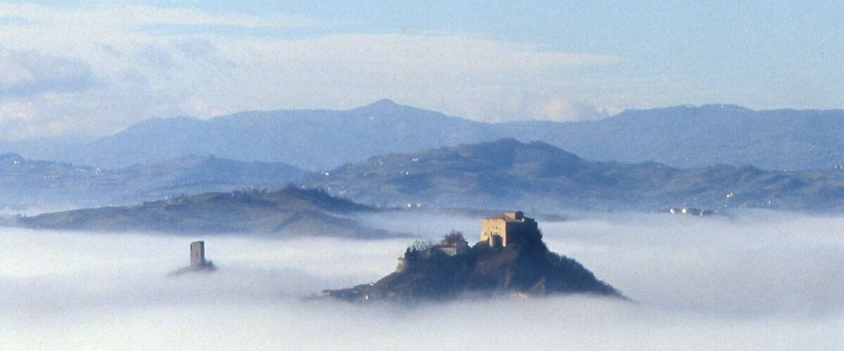 A castle on a hill surrounded by fog.