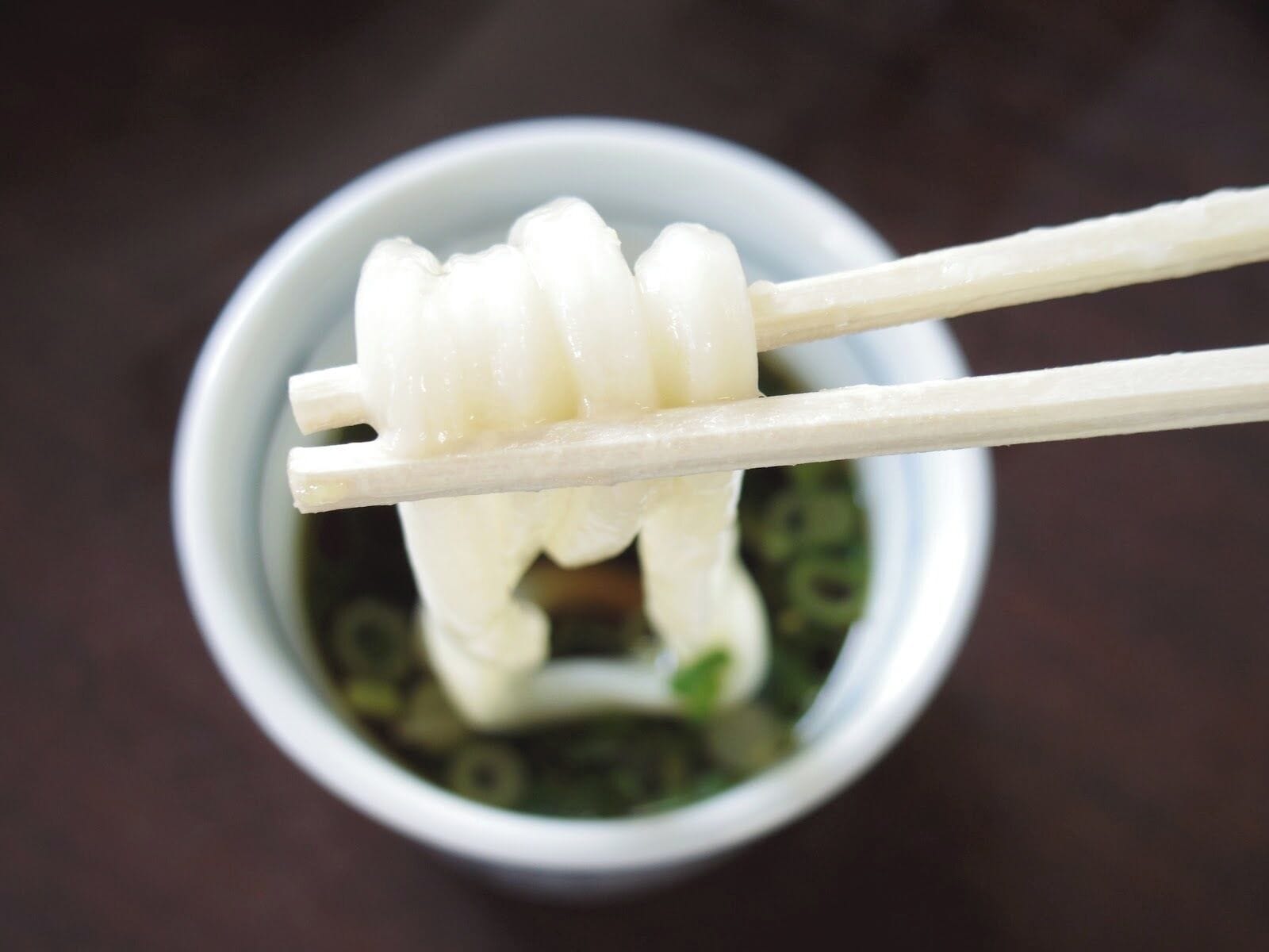 A bowl of white noodles with chopsticks.