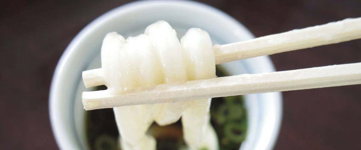 A bowl of white noodles with chopsticks.