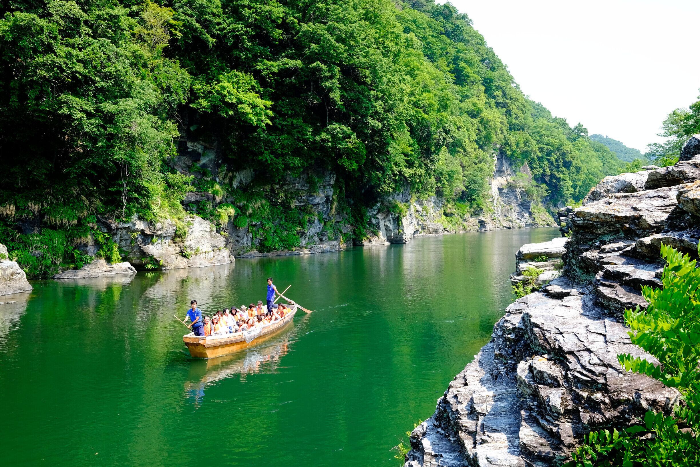 A boat with passengers on a river surrounded by lush green hills.