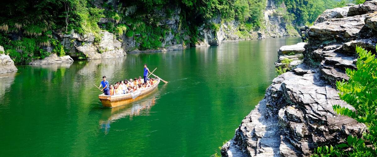 A boat with passengers on a river surrounded by lush green hills.