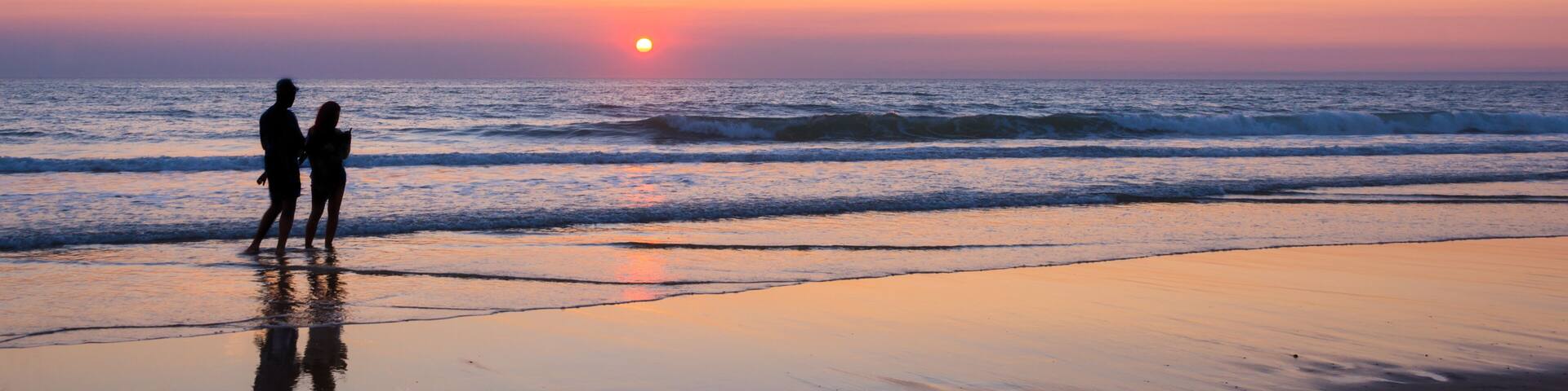 Silhouettes of a couple enjoying the sunset on the atlantic ocean, Lacanau France