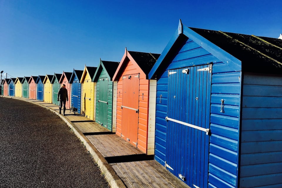 A row of colorful beach huts along a seaside promenade.
