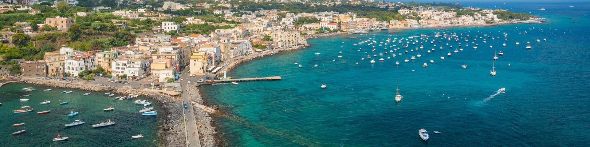 A coastal town with a pier, boats, and a mountainous backdrop.
