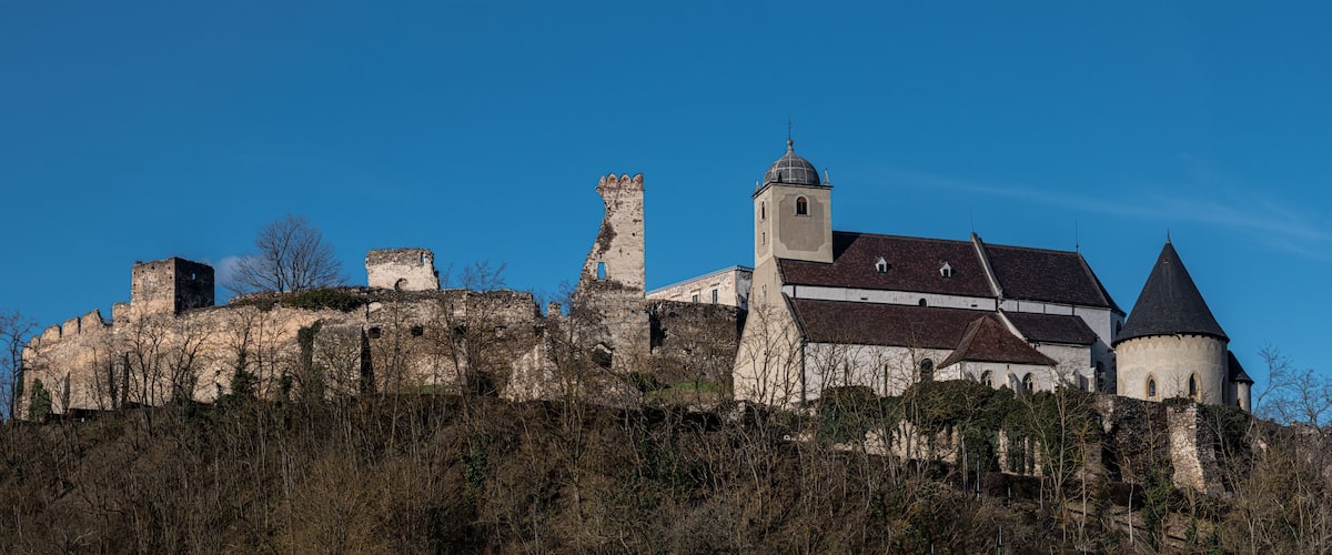 A historic castle with a prominent tower and a church on a hill.