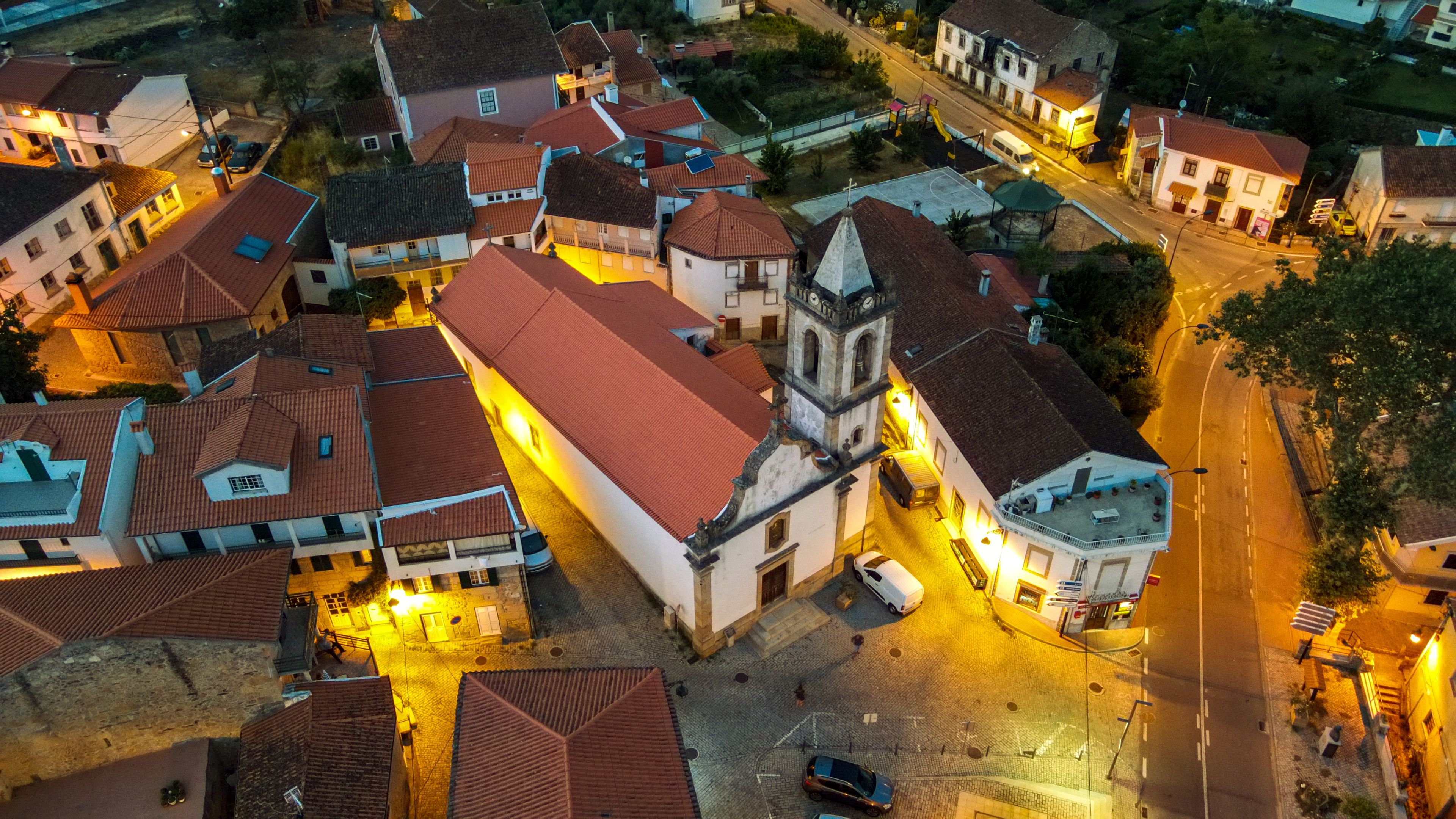 Ein Luftbild einer Stadt mit roten Dächern, einer markanten Kirche mit Glockenturm und einer breiten Hauptstraße.