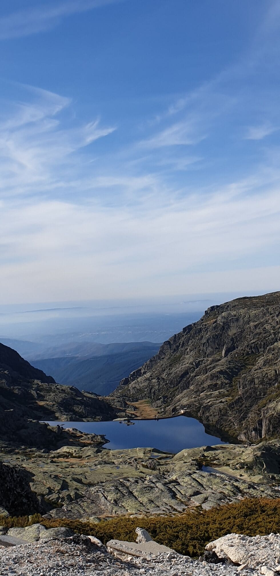 Paisaje montañoso con un lago rodeado de terreno rocoso y vegetación escasa.