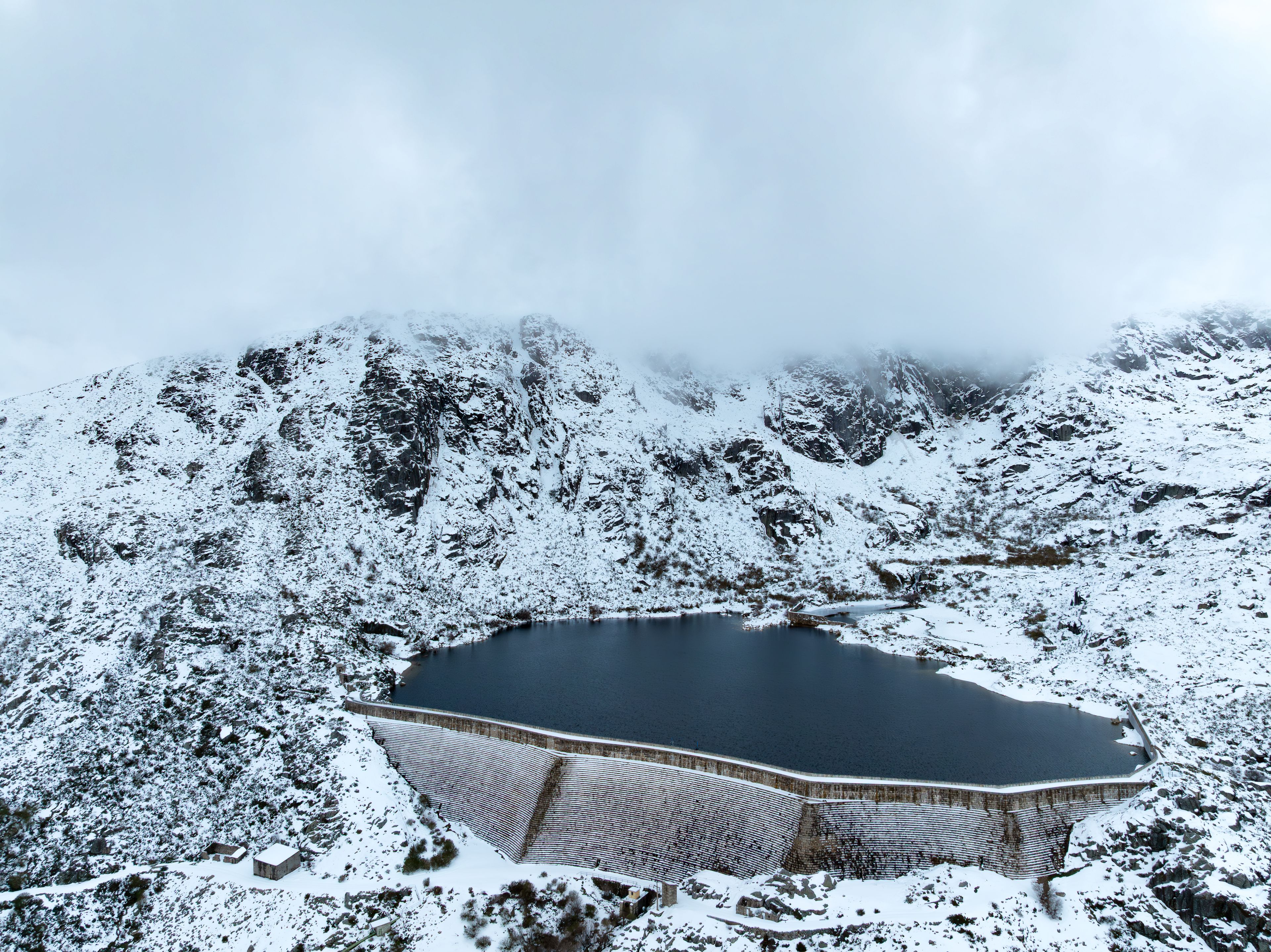Eine verschneite Berglandschaft mit einem großen Stausee und einem See.
