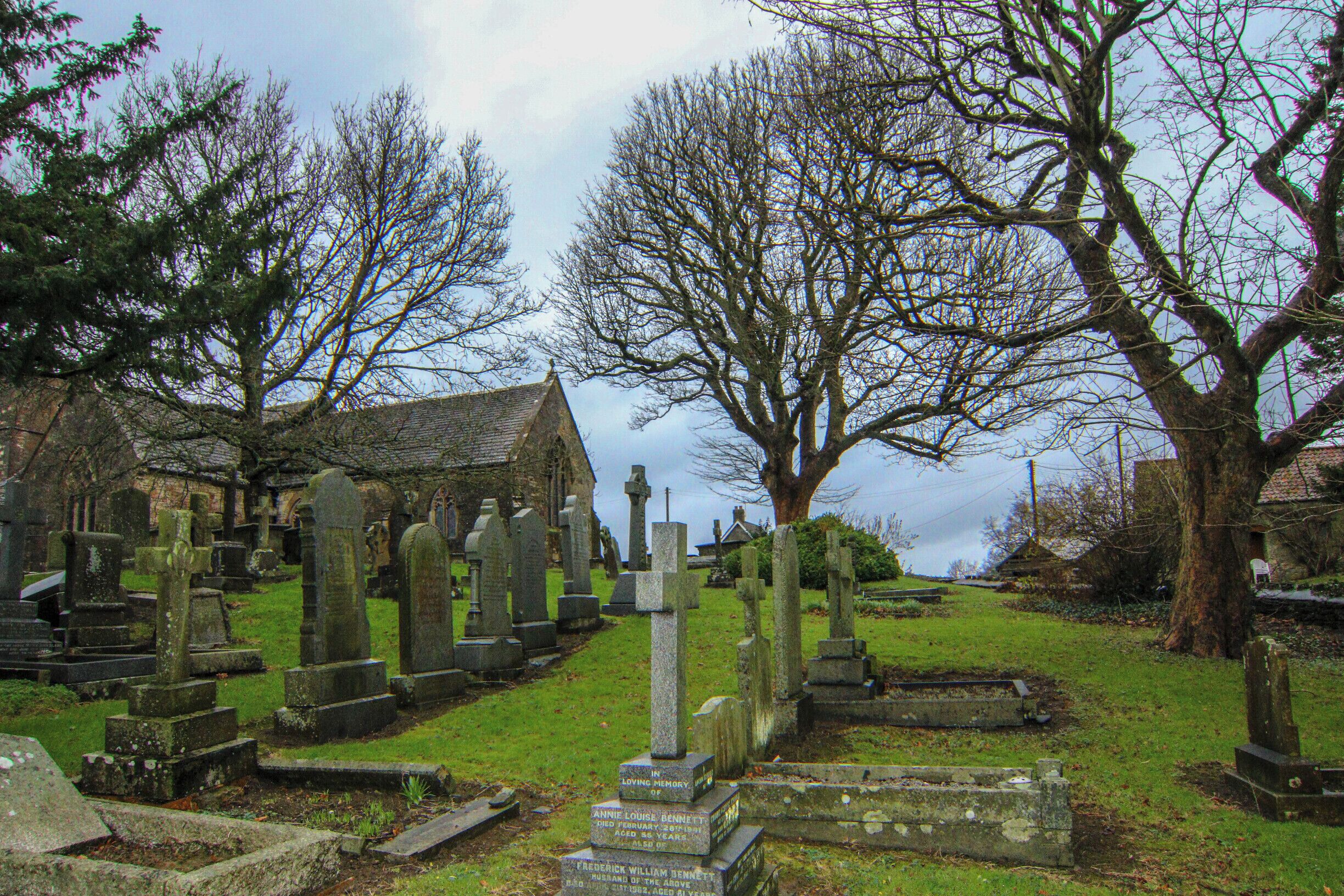 A cemetery with numerous gravestones and a church in the background.