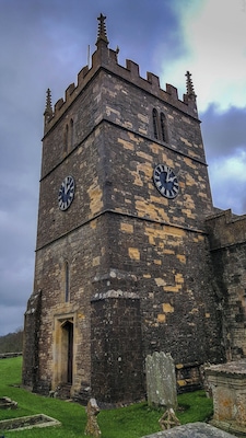 Una torre histórica con dos grandes relojes y una pequeña entrada.