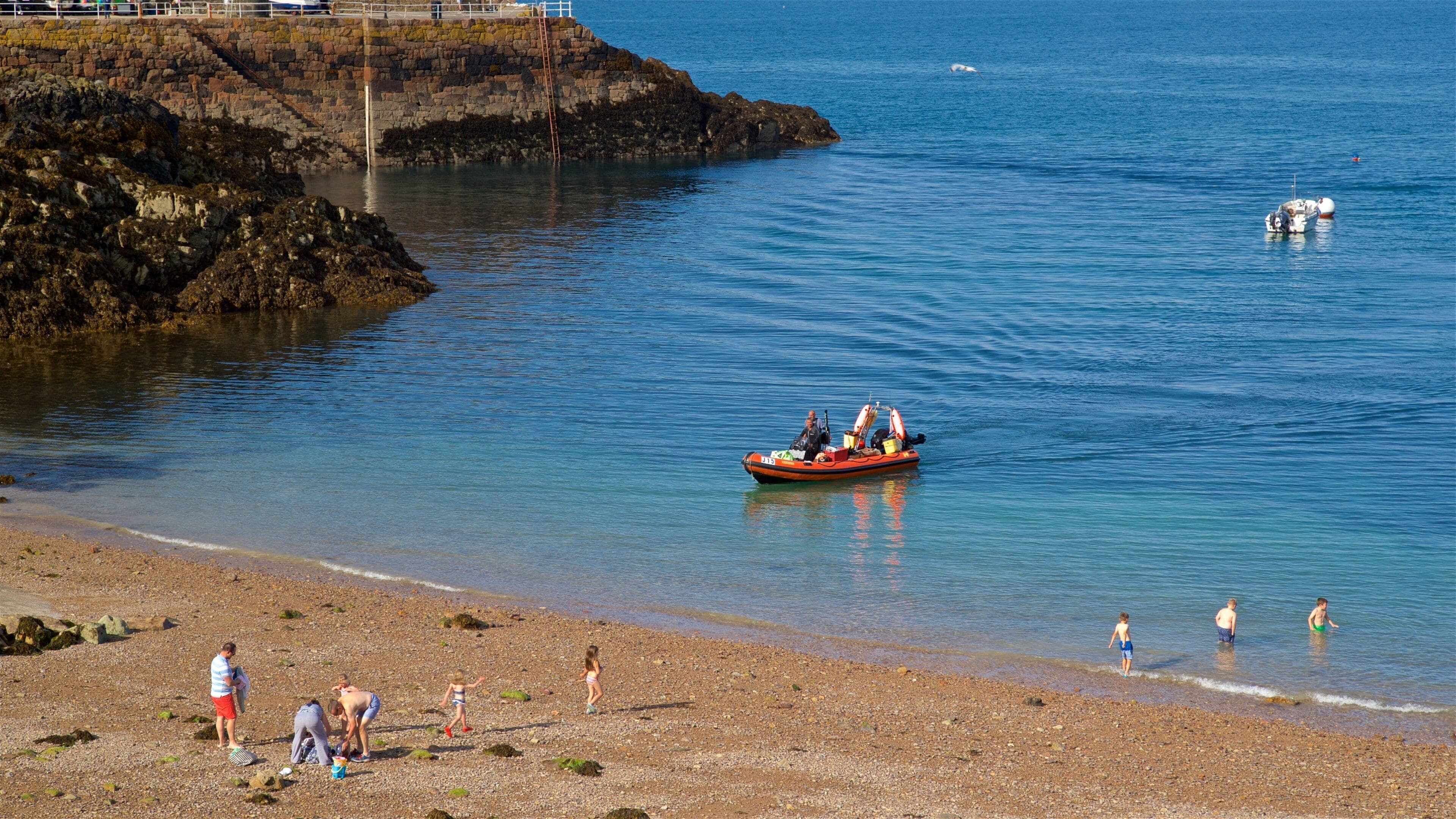 Bouley Bay som inkluderer strand med småstein, båter og kyst