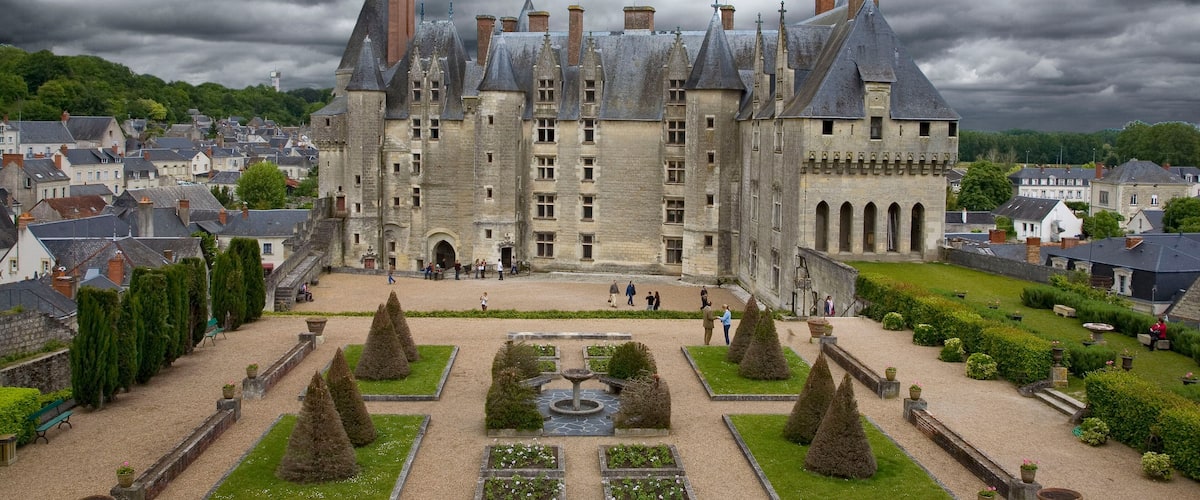 A historic castle with a symmetrical garden, surrounded by a town.