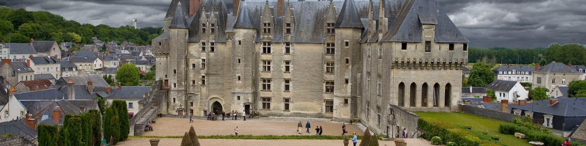 A historic castle with a symmetrical garden, surrounded by a town.