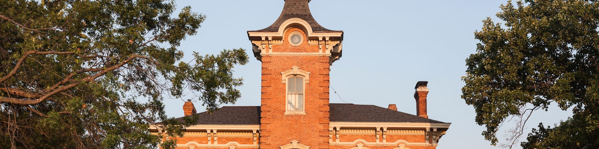 A large brick Victorian house with a prominent tower and a wrap-around porch.