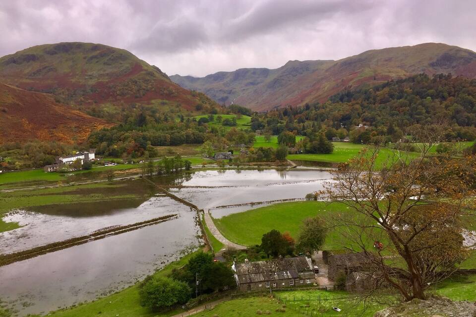 A valley with a lake, green fields, and a stone house.
