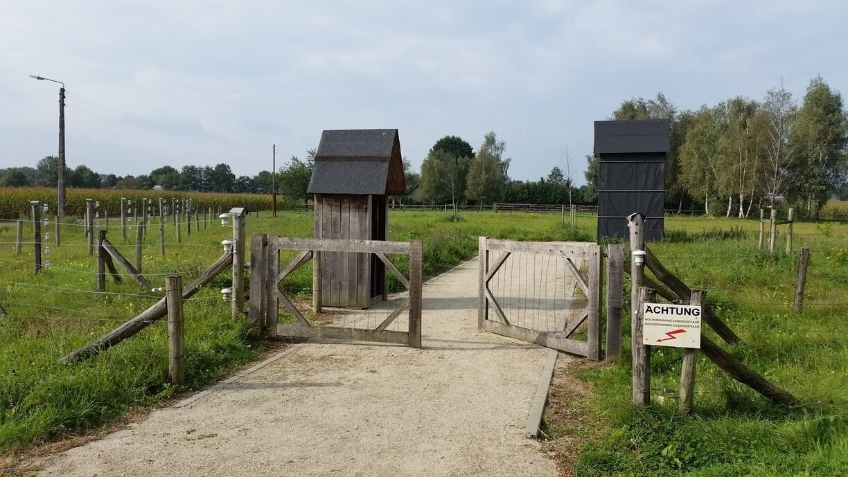 A wooden gate with a sign reading "ACHTUNG" in a rural setting.