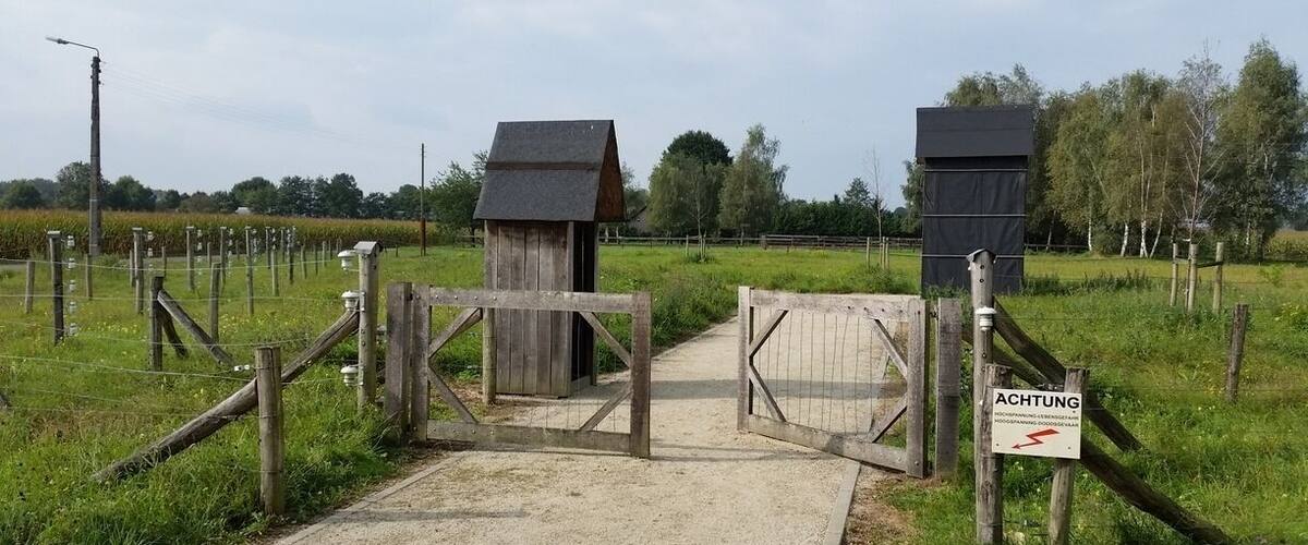 A wooden gate with a sign reading "ACHTUNG" in a rural setting.