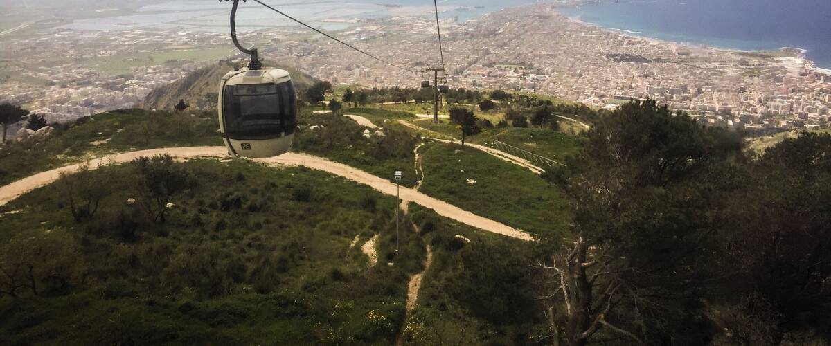 A cable car over a coastal city with a clear view of the sea and urban landscape.