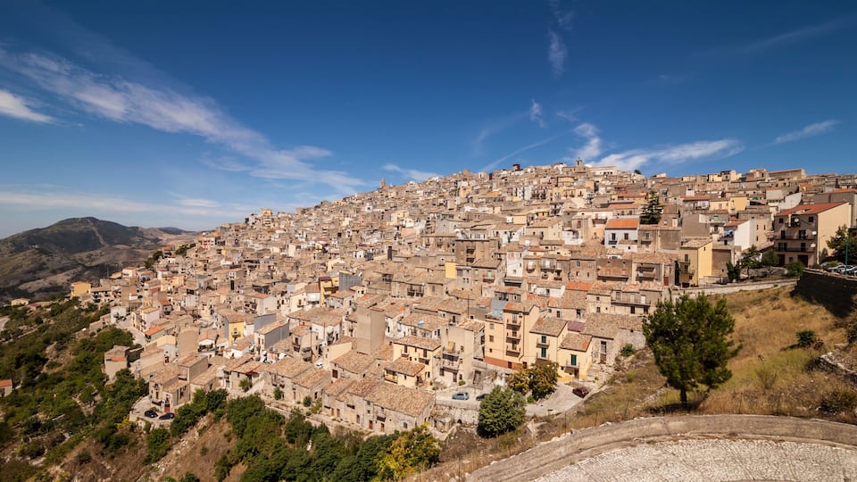 A densely packed hillside town with historic buildings and a clear blue sky.