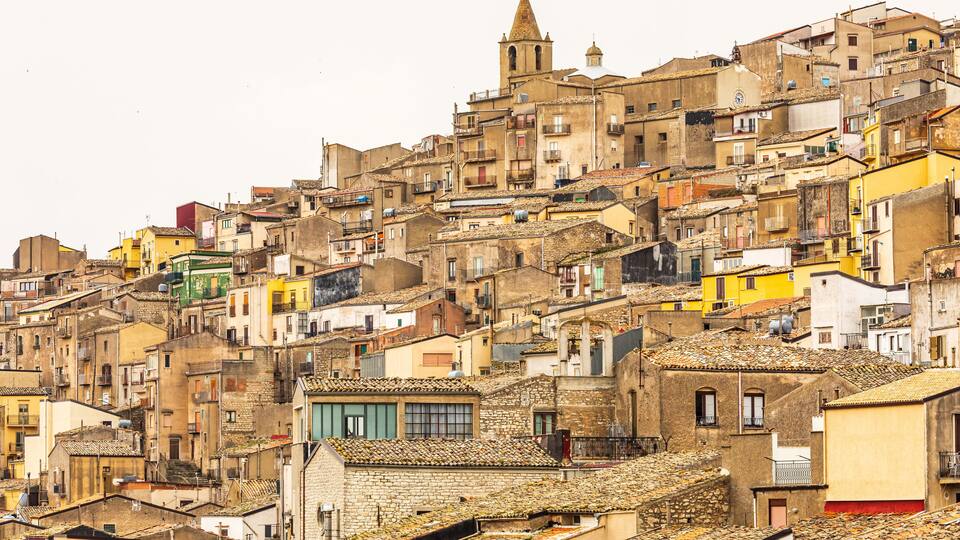 A densely packed hillside of historic buildings with a prominent church steeple.