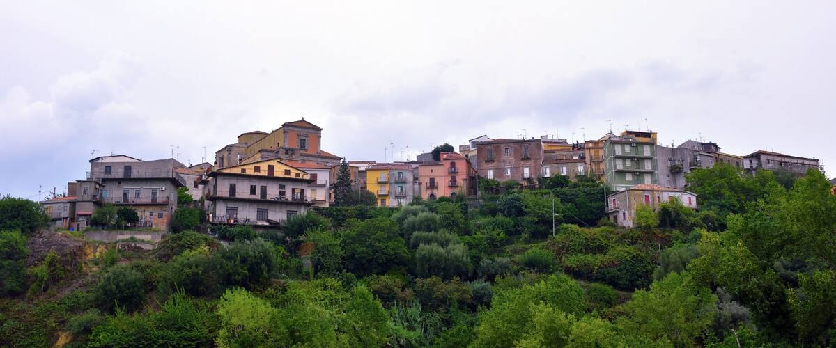 A hillside town with colorful buildings and dense green vegetation.