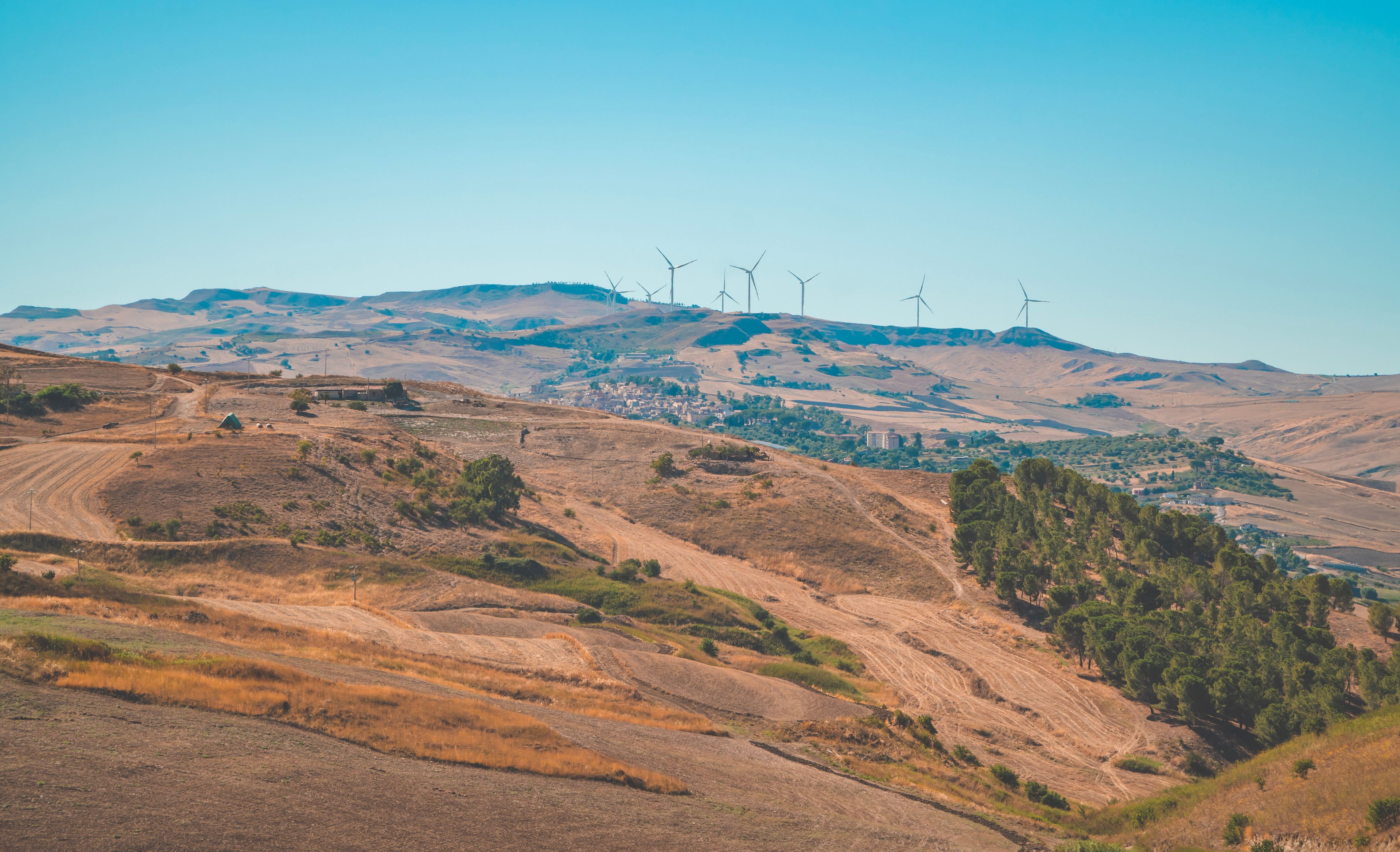 A hilly landscape with wind turbines and a small settlement.