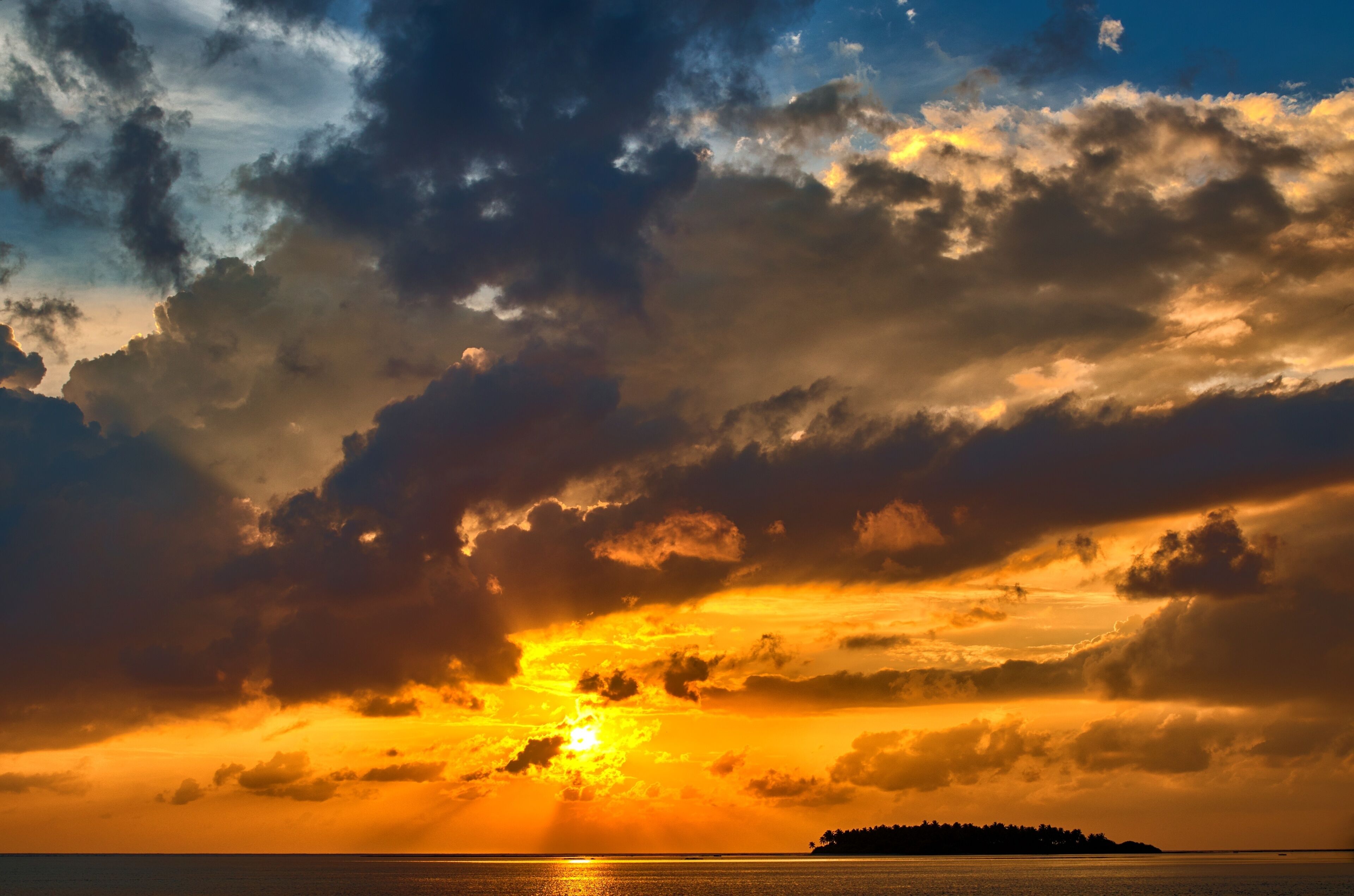 A sunset over a body of water with a distant landmass.