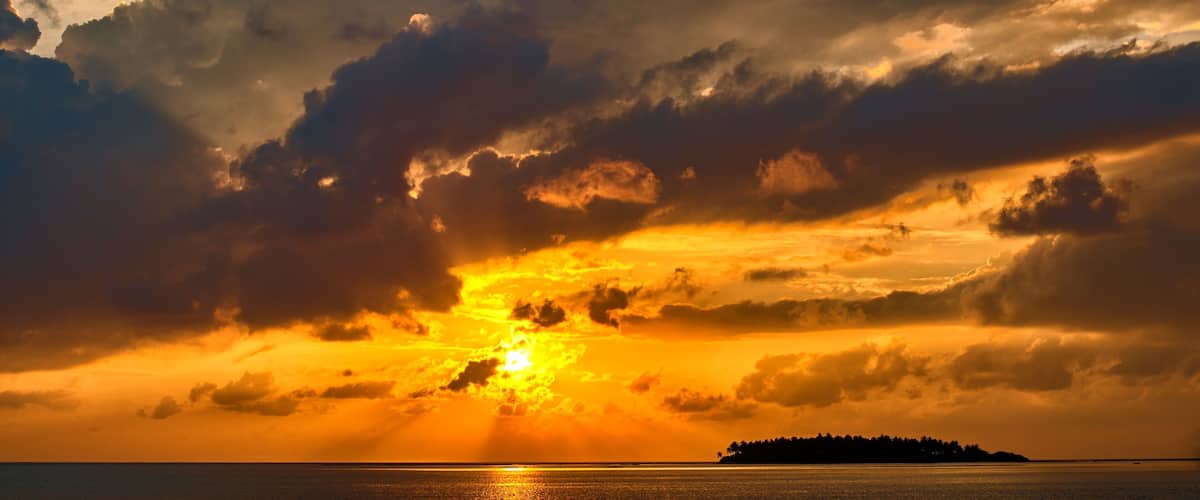 A sunset over a body of water with a distant landmass.