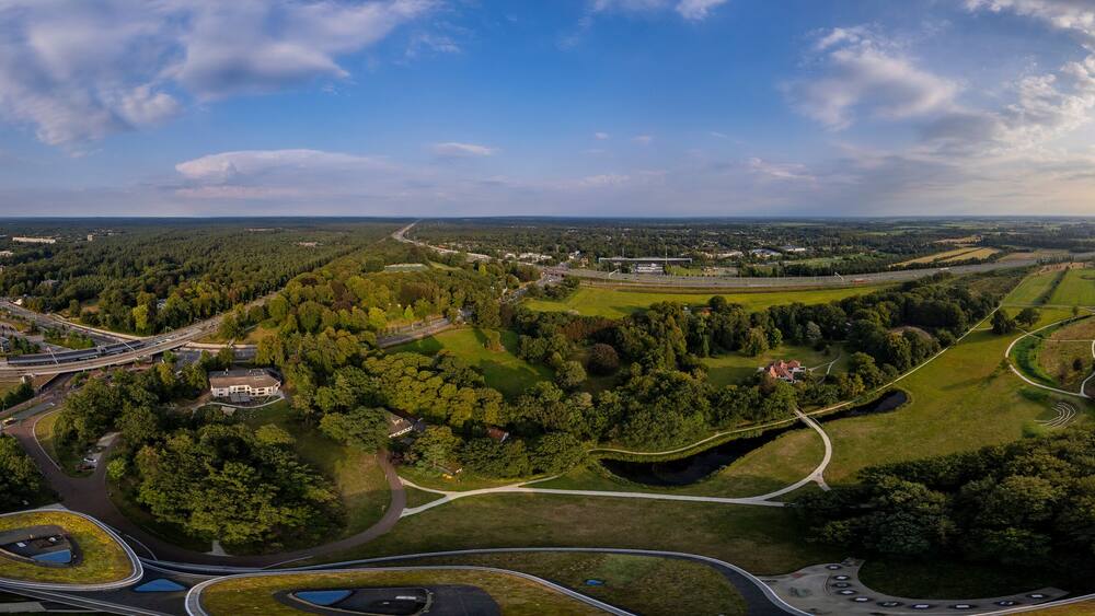 Super wide 180 degrees aerial panorama of Triodos bank in green park surrounding of Driebergen Zeist with train station and highway in the background