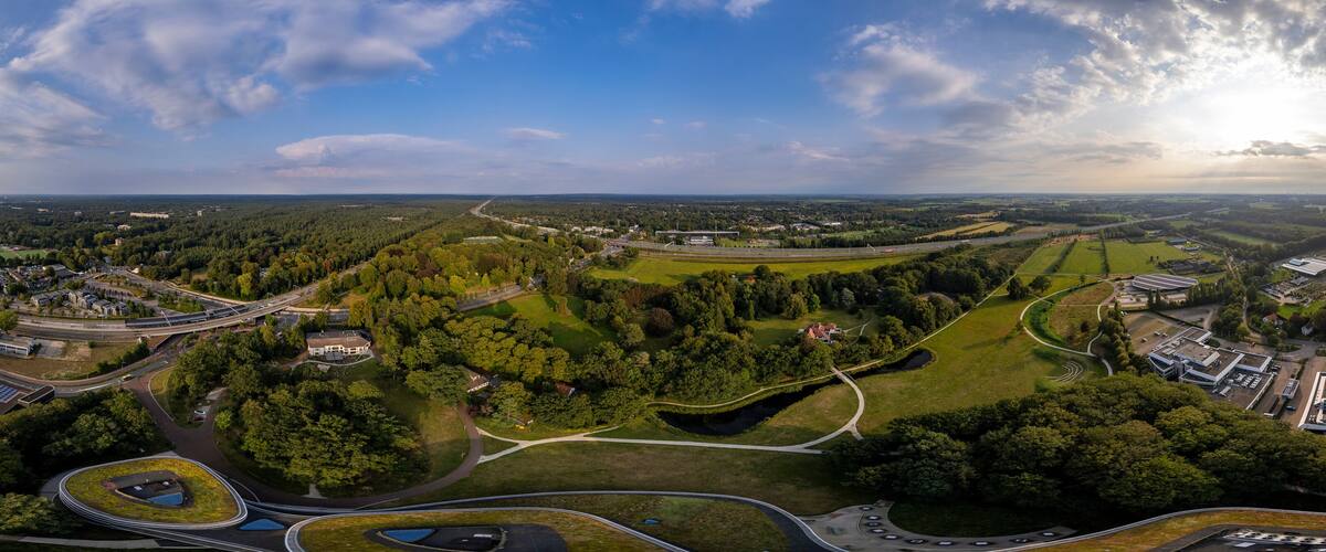 Super wide 180 degrees aerial panorama of Triodos bank in green park surrounding of Driebergen Zeist with train station and highway in the background
