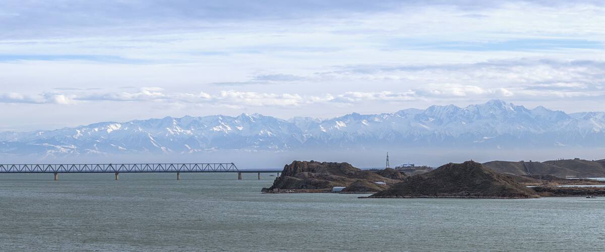 A bridge over a body of water with mountains in the background.