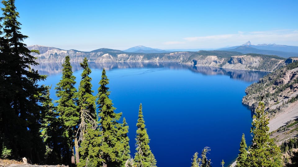 A clear view of a large lake surrounded by mountains and evergreen trees.