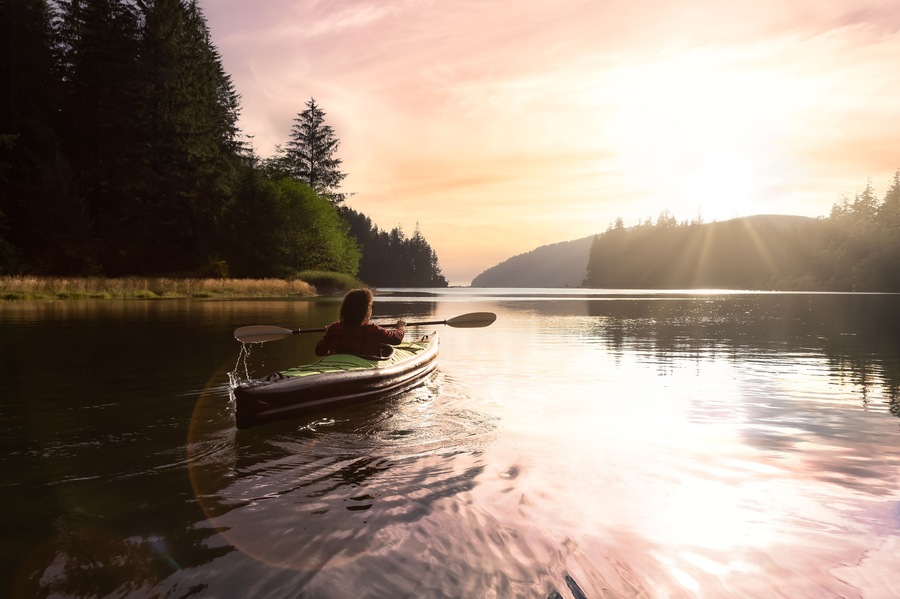 Adventurous Girl kayaking in the Pacific Ocean. Sunset Sky Art Render. Taken in San Josef Bay, Cape Scott, Northern Vancouver Island, British Columbia, Canada. Adventure Travel Concept