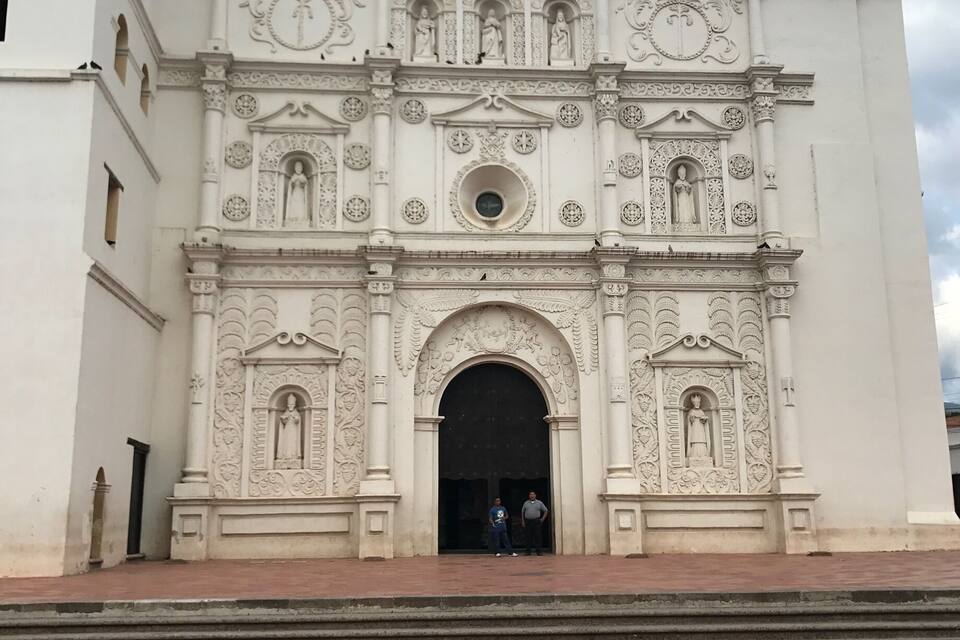 A white colonial-style church with ornate carvings and statues.