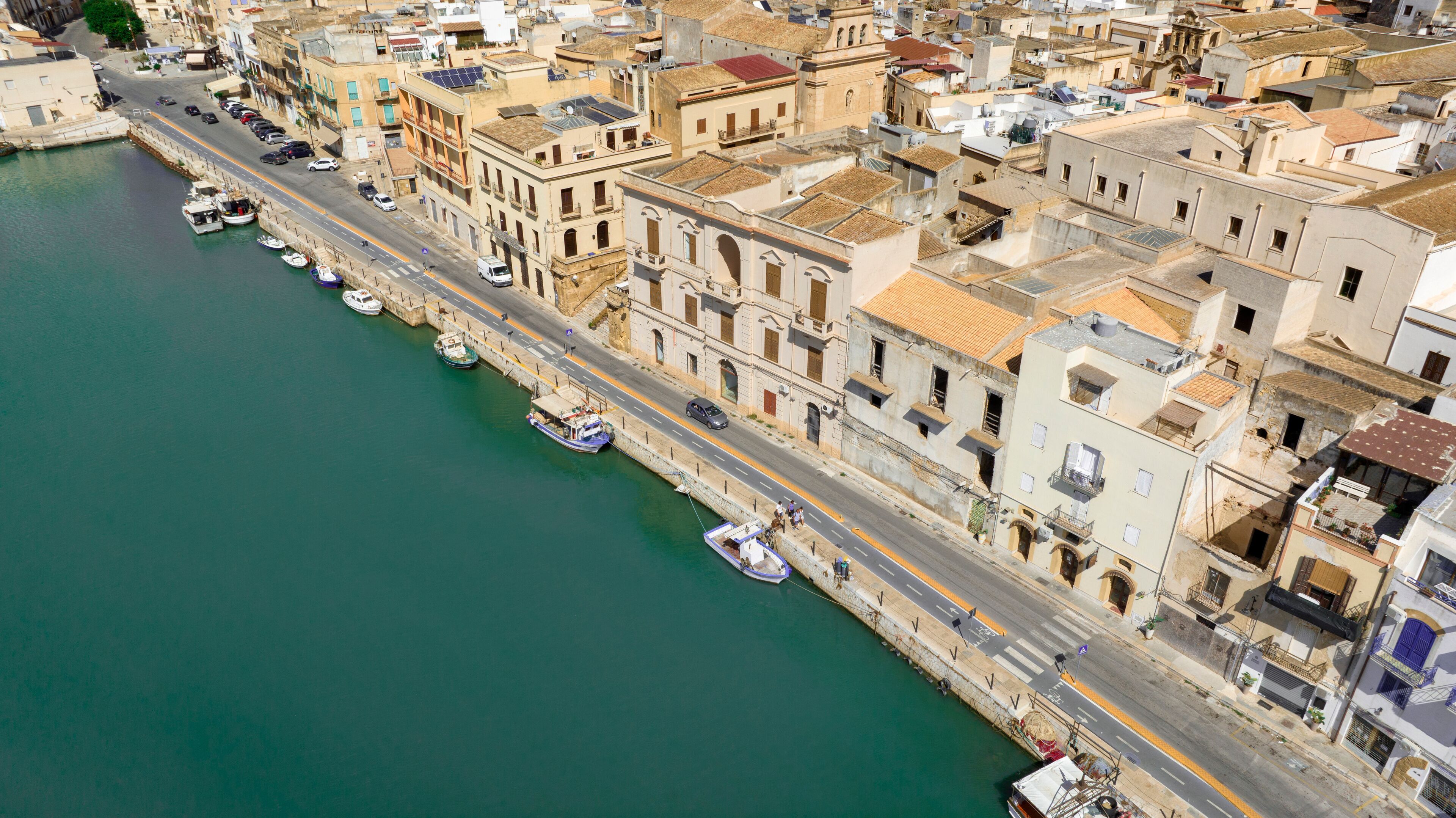 Aerial view of houses and buildings built along a canal. It's Mazaro river, located in the historic center of Mazara del Vallo, in the province of Trapani, Sicily, Italy. It's a beautiful sunny day.