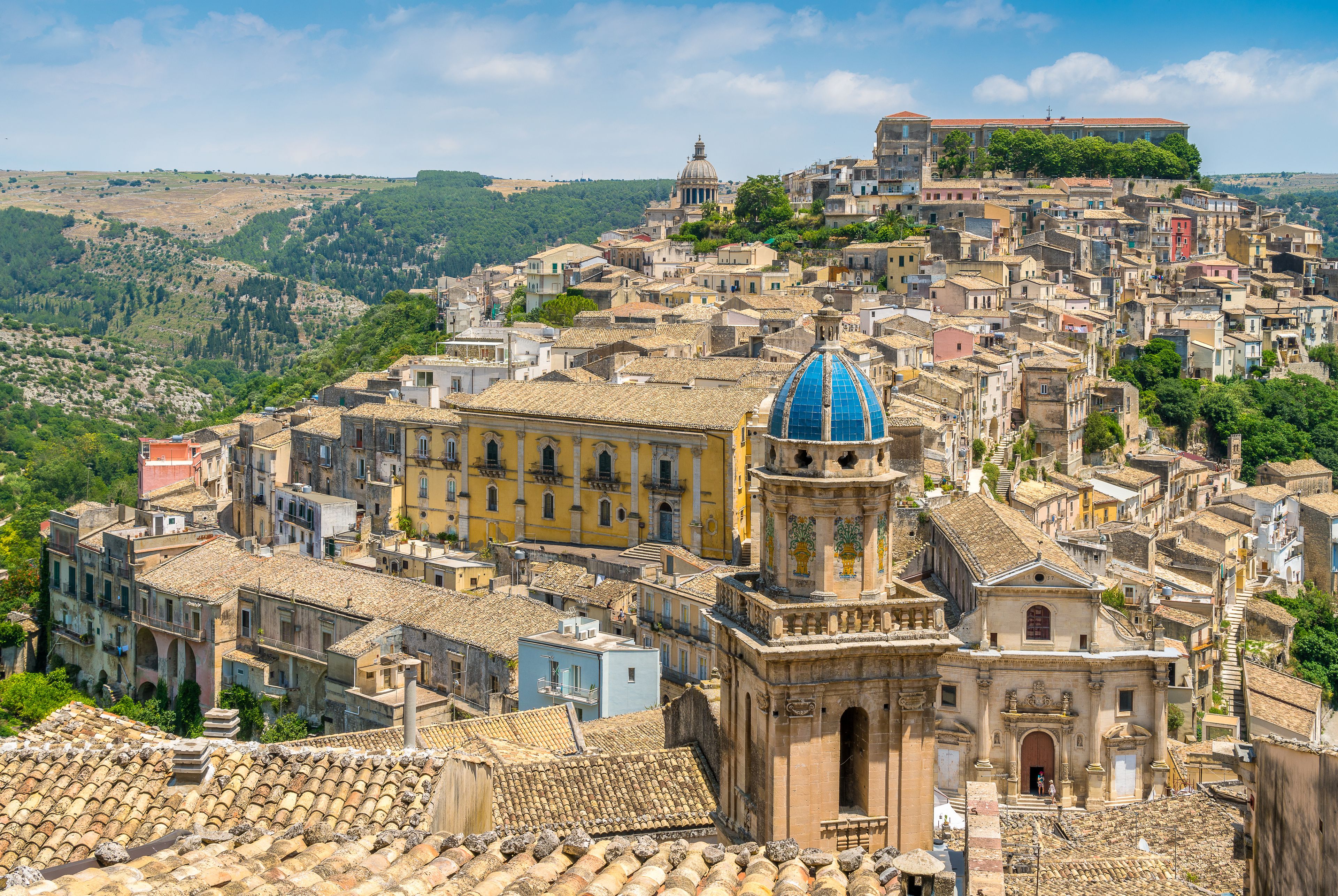Une ville pittoresque, construite à flanc de colline, où les bâtiments sont très rapprochés les uns des autres et où l’on trouve une architecture historique remarquable, notamment une église imposante avec un dôme bleu et un clocher.