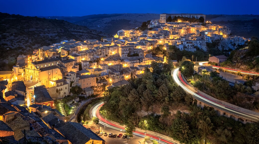 Une ville historique au crépuscule, avec ses bâtiments illuminés et ses rues sinueuses.