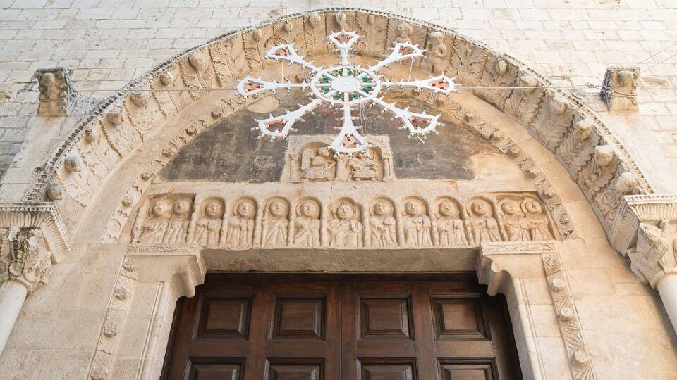 A stone archway with intricate carvings and a wooden door.