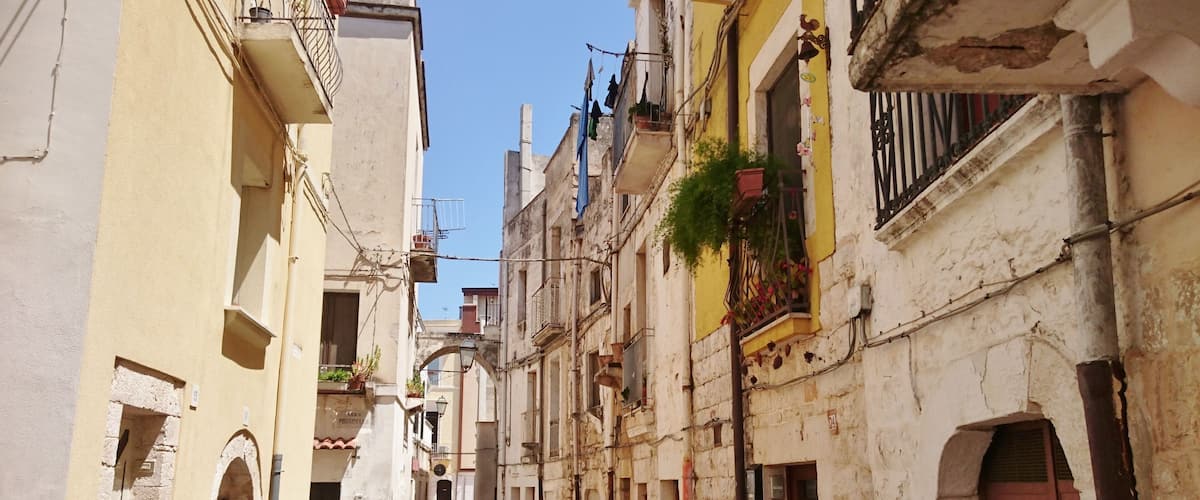 A narrow street lined with old buildings, some with balconies and laundry hanging out to dry.