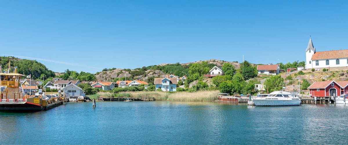 A harbor with boats, a large yellow ship, and houses on a hillside.